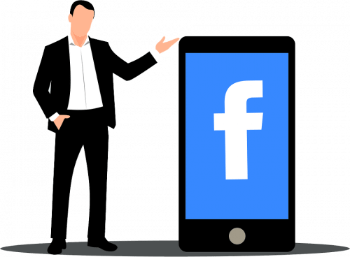 man standing beside giant smartphone with facebook logo on screen