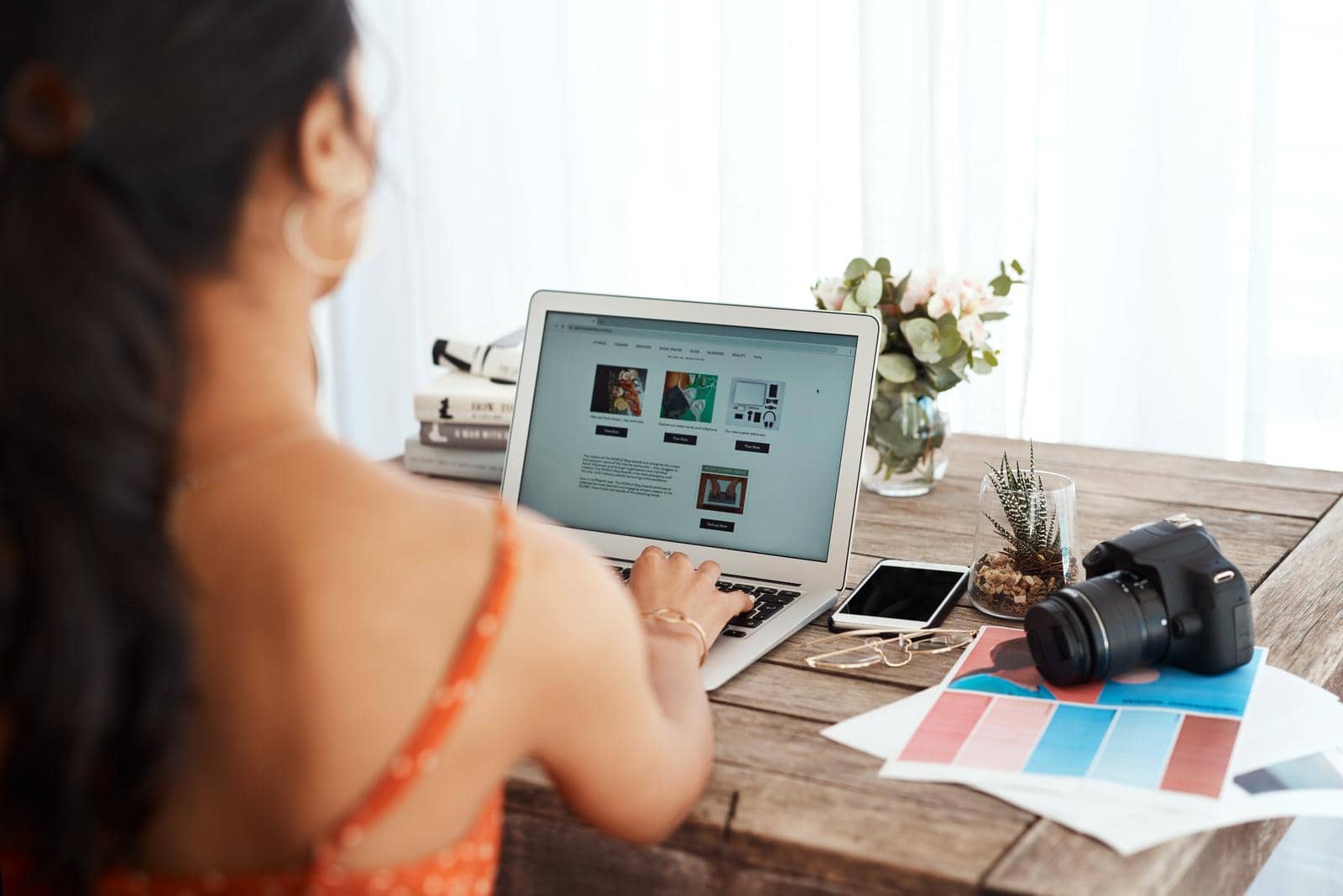 A woman sitting at a table with a laptop and a camera. A woman sitting at a table with a laptop and a camera.